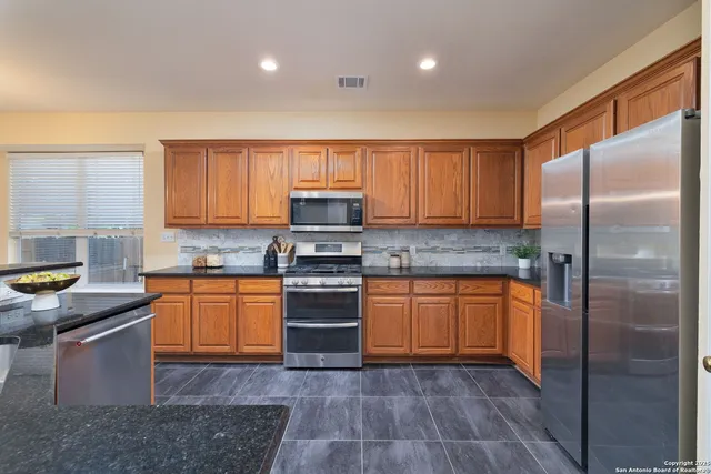 a kitchen with stainless steel appliances granite countertop a stove a sink dishwasher a refrigerator and a microwave