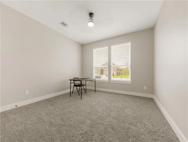 an empty room with windows and chair