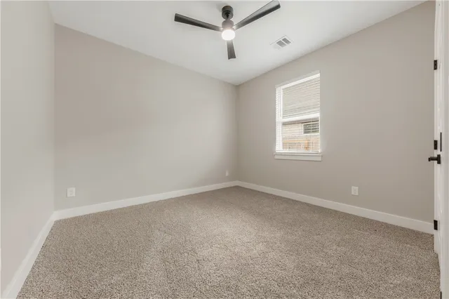 an empty room with a window and a ceiling fan