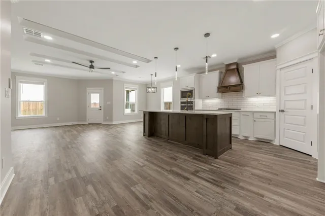 a large kitchen with stainless steel appliances granite countertop a large counter top a sink and a refrigerator