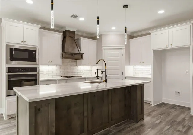 a kitchen with kitchen island a sink stainless steel appliances and cabinets