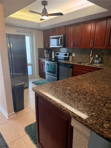 a kitchen with kitchen island granite countertop wooden cabinets and a stainless steel refrigerator