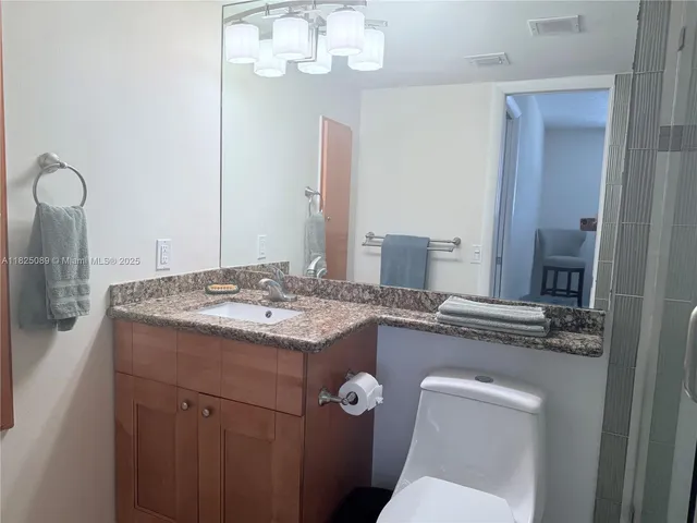 a bathroom with a granite countertop sink a toilet and a mirror