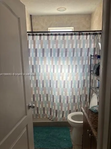 a bathroom with a granite countertop sink and a toilet