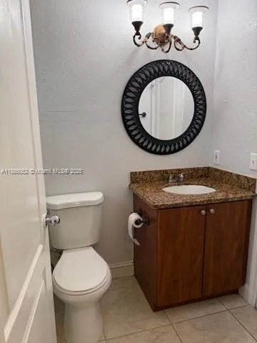 a bathroom with a granite countertop toilet and a sink
