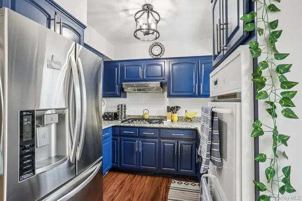 a kitchen with stainless steel appliances granite countertop a refrigerator a sink and wooden cabinets