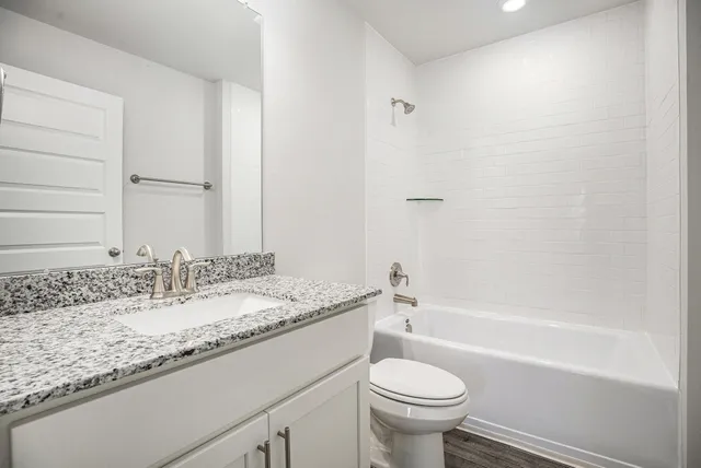 a bathroom with a granite countertop sink a toilet and bathtub