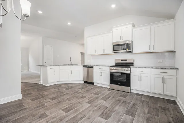 a kitchen with granite countertop white cabinets and appliances