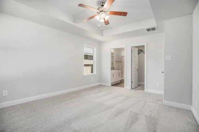 an empty room with windows and ceiling fan