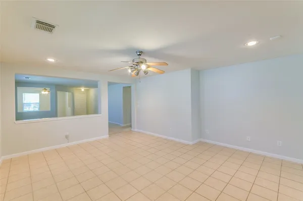 a view of an empty room with chandelier fan