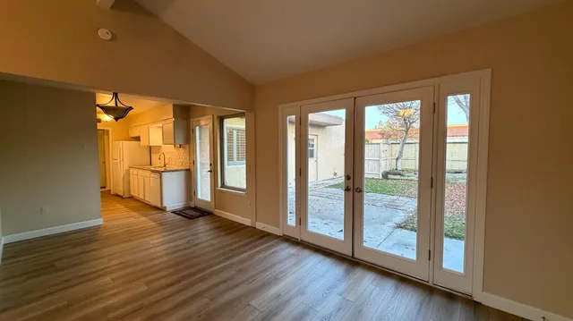 a view of an empty room with wooden floor and a window