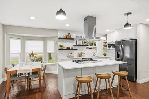 a living room with couches and kitchen view with wooden floor