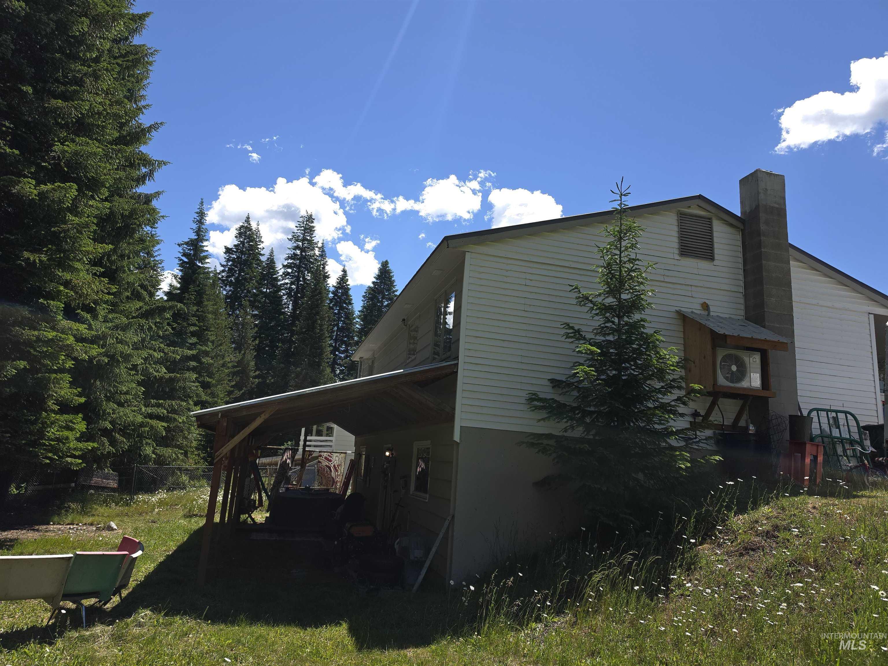 138 Timberline Drive Pierce, ID 83546 - Photo 29 of 29 Exterior featuring white horizontal siding, a prominent concrete chimney, and an attached covered carport