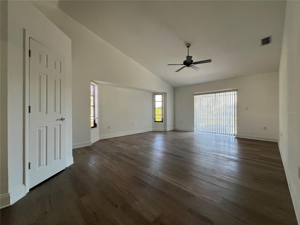 2092 Rio De Janeiro Avenue Punta Gorda, FL 33983 - Photo 17 of 50 an empty room with wooden floor chandelier fan and windows