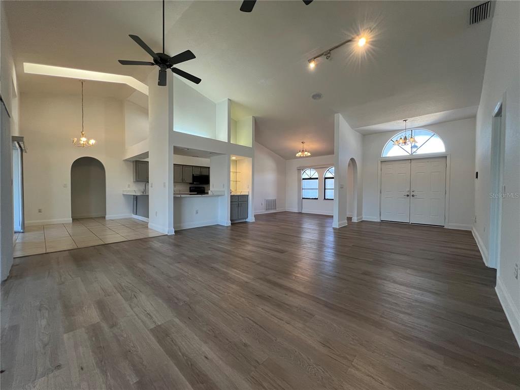 2092 Rio De Janeiro Avenue Punta Gorda, FL 33983 - Photo 9 of 50 an empty room with wooden floor a ceiling fan windows and a fireplace