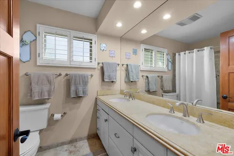 a spacious bathroom with double vanity a toilet a mirror and a shower