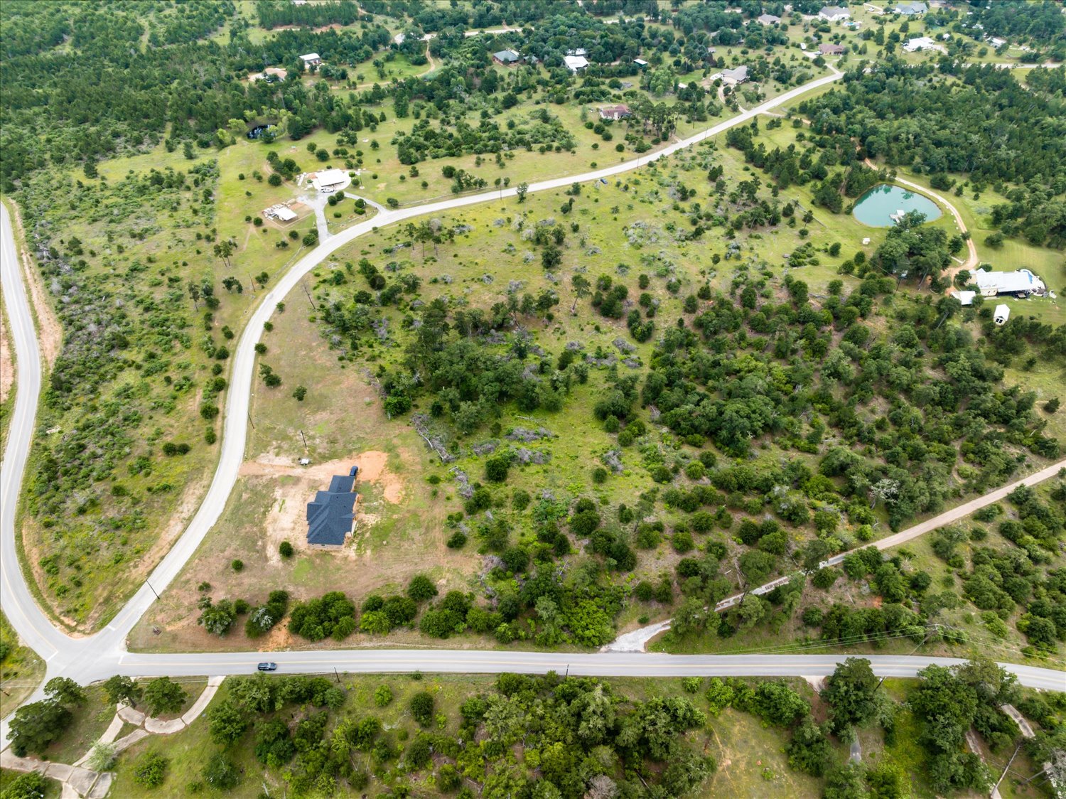 0 McAllister Road Bastrop, TX 78602 - Photo 3 of 12 Vast, verdant landscape with winding roads and a tranquil pond, perfect for your custom dream home.