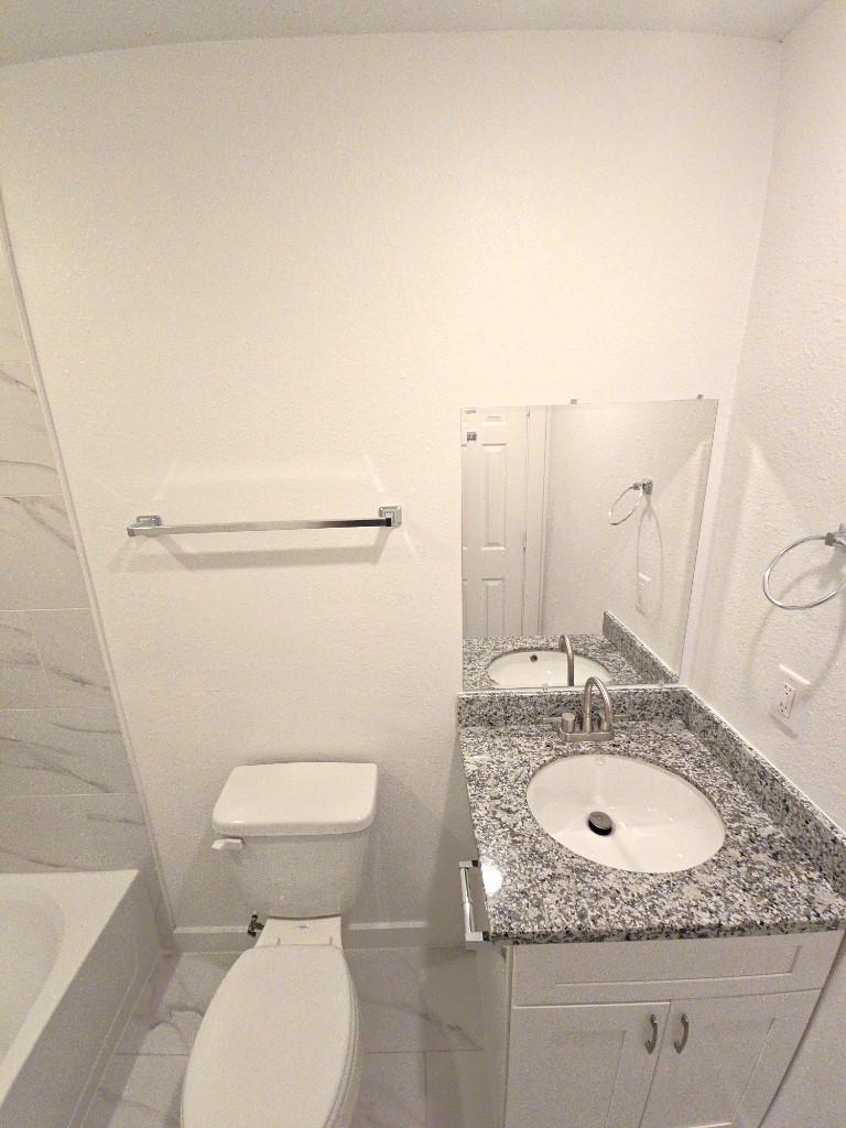 6315 Sandra Street, Unit A Houston, TX 77028 - Photo 16 of 21 a bathroom with a granite countertop toilet sink and mirror