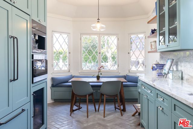 a dining room with stainless steel appliances granite countertop a dining table chairs a window and kitchen view