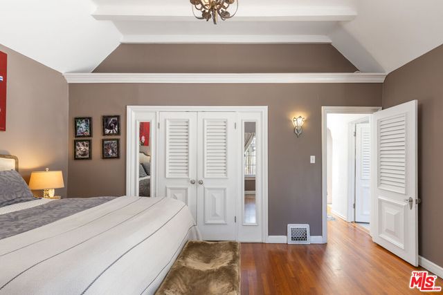 a bedroom with a large bed and wooden floor