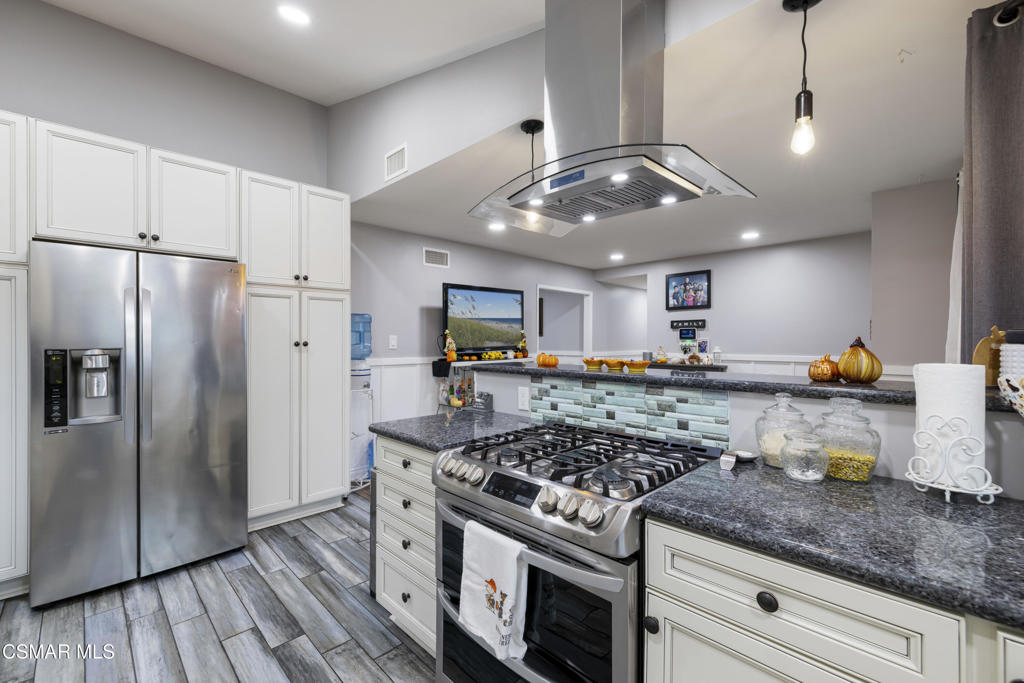 1231 Bluebell Street Oxnard, CA 93036 - Photo 13 of 44 a kitchen with stainless steel appliances granite countertop a stove a refrigerator and a wooden cabinets
