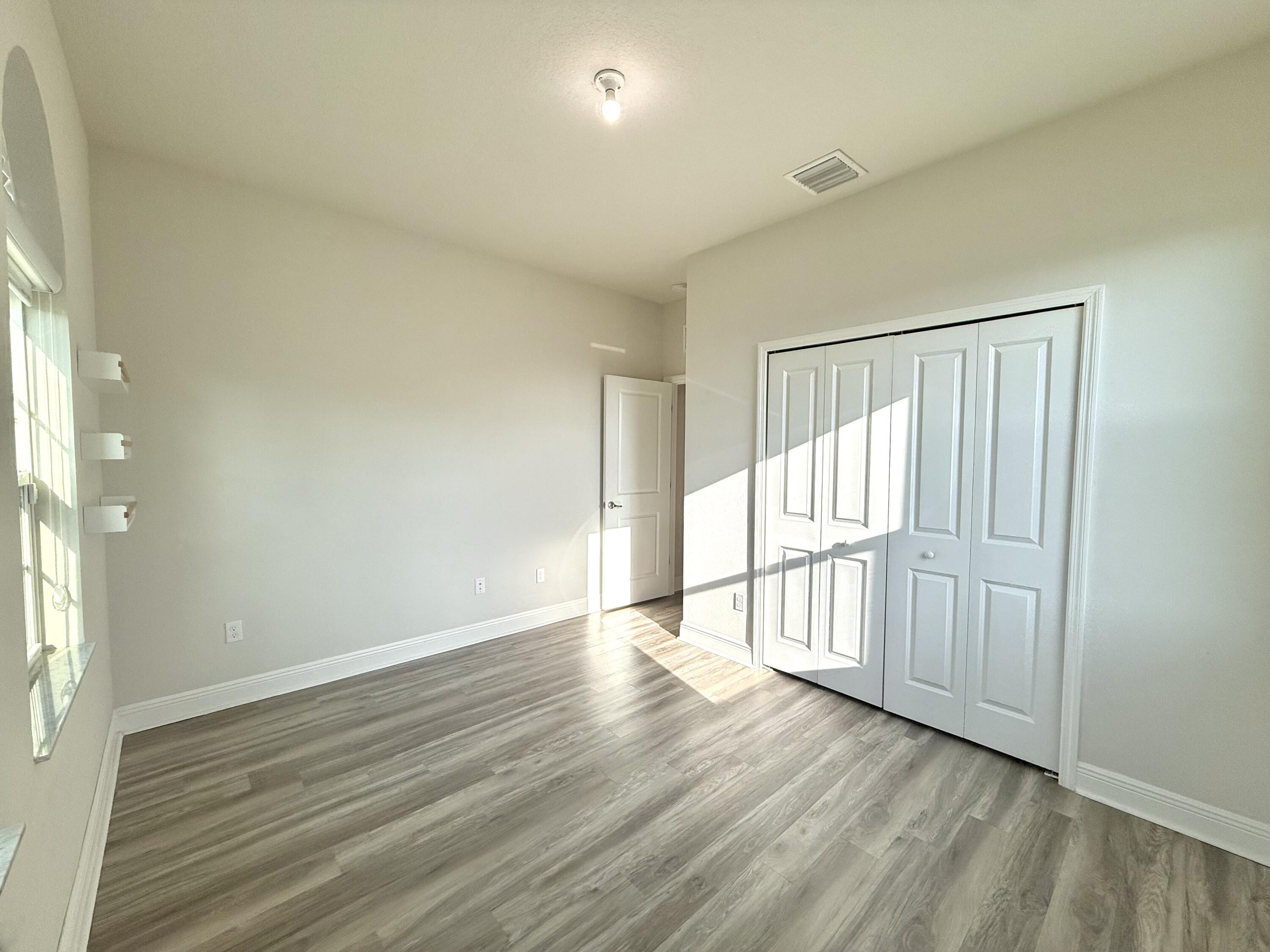 10819 Southwest Pacini Way Port St. Lucie, FL 34987 - Photo 12 of 43 a view of an empty room with wooden floor and a window