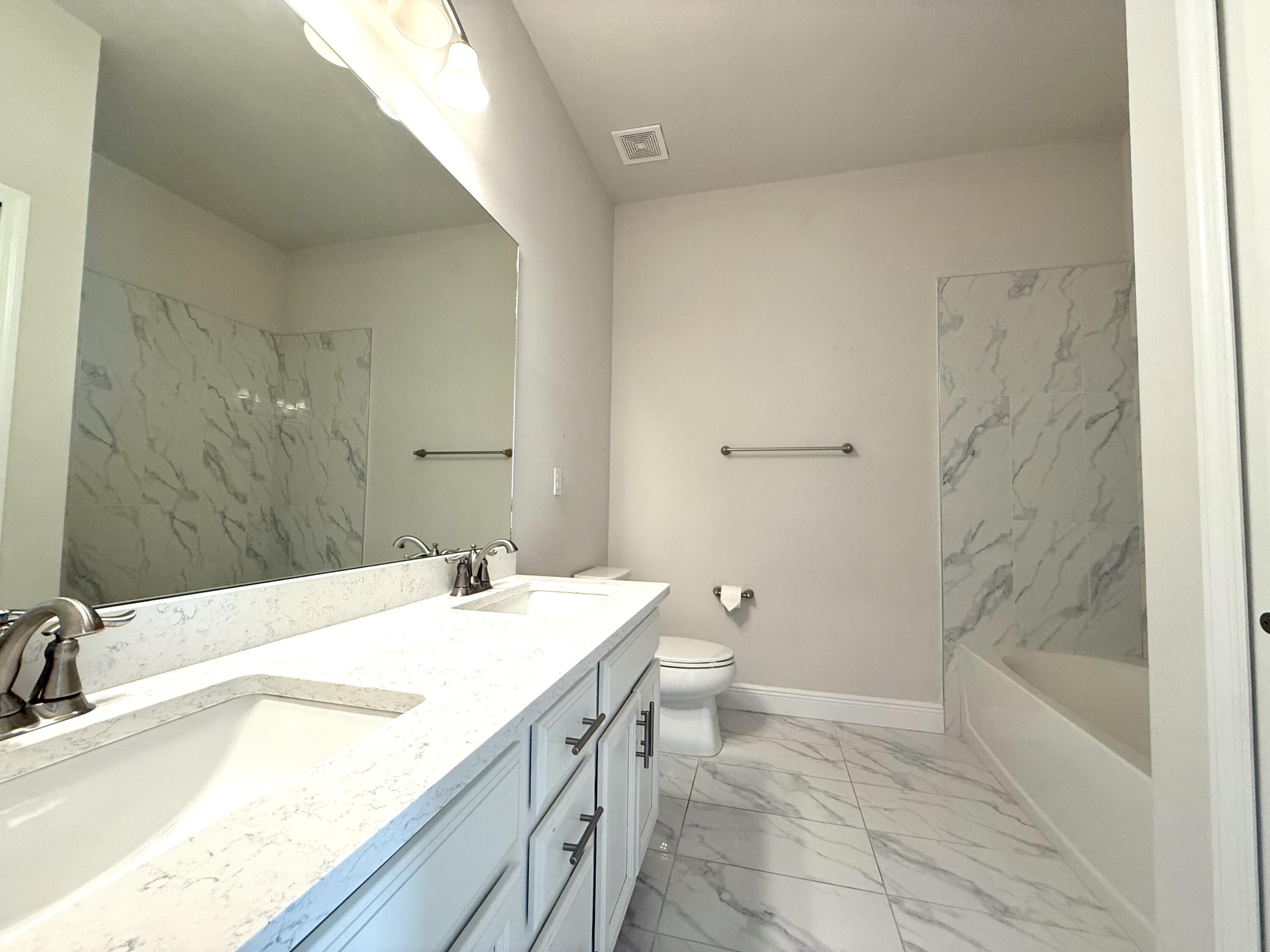 10819 Southwest Pacini Way Port St. Lucie, FL 34987 - Photo 13 of 43 a bathroom with a granite countertop sink a toilet and bathtub