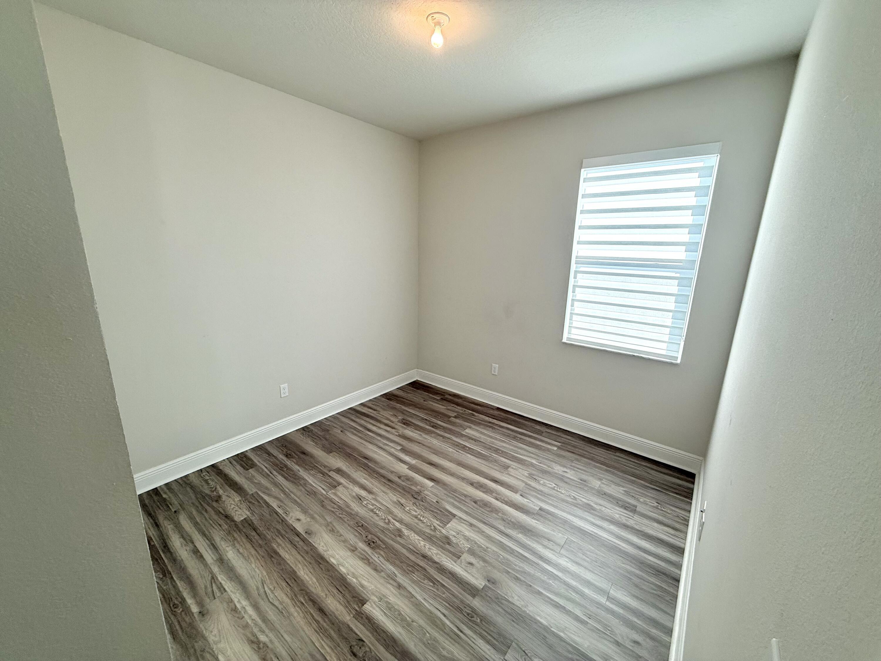10819 Southwest Pacini Way Port St. Lucie, FL 34987 - Photo 14 of 43 an empty room with wooden floor and windows