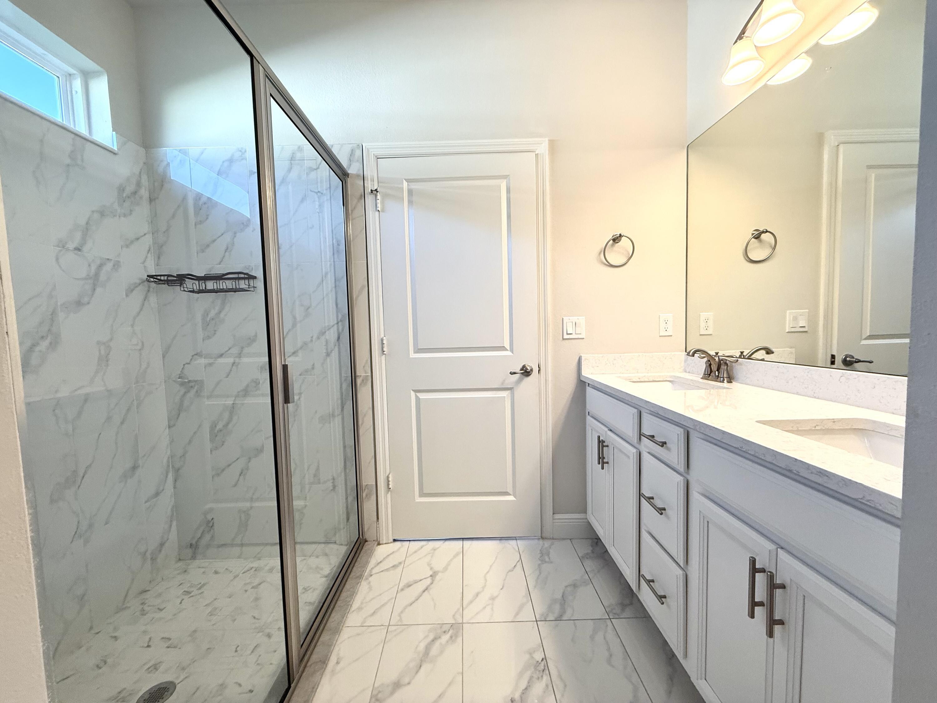 10819 Southwest Pacini Way Port St. Lucie, FL 34987 - Photo 27 of 43 a spacious bathroom with a granite countertop sink mirror and shower