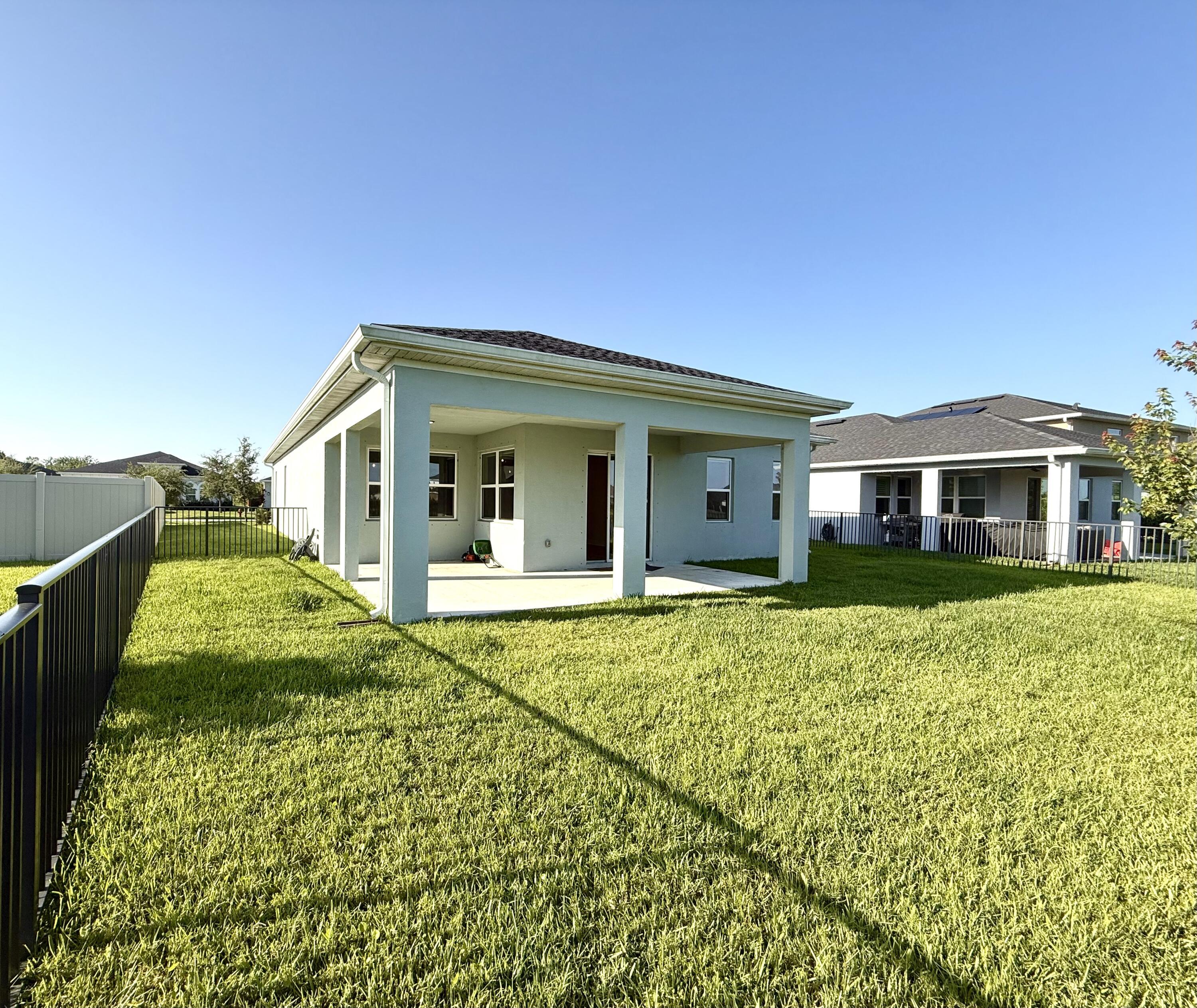 10819 Southwest Pacini Way Port St. Lucie, FL 34987 - Photo 28 of 43 a view of a white house with a large window and potted plants