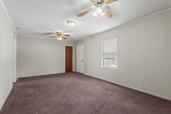 an empty room with a chandelier fan and windows