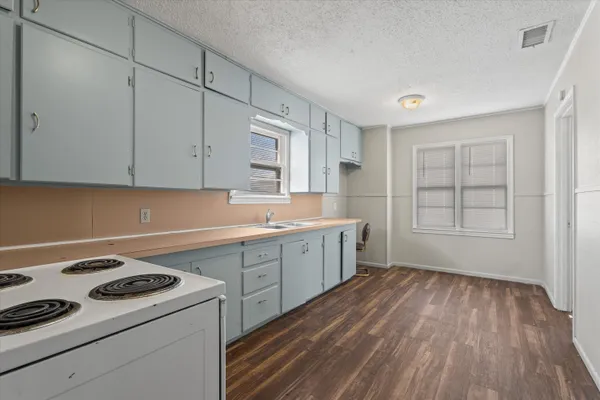 a kitchen with a hard wood floor white cabinets and white appliances
