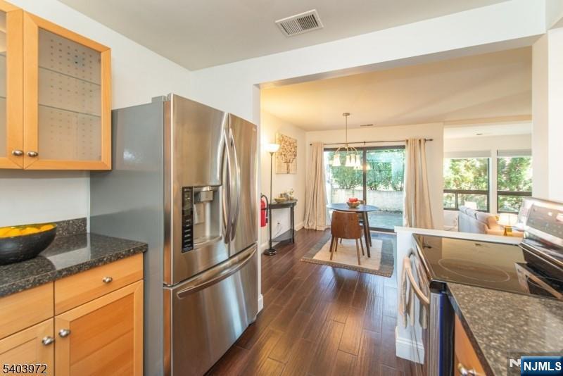 105 River Road, Unit C1 Nutley, NJ 07110 - Photo 12 of 22 a kitchen with stainless steel appliances granite countertop a refrigerator a sink dishwasher a stove and a dining table with wooden floor