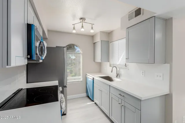 a kitchen with a sink dishwasher a refrigerator and cabinets