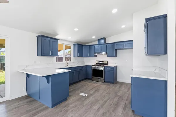 a kitchen with stainless steel appliances kitchen island granite countertop a sink stove and wooden cabinets