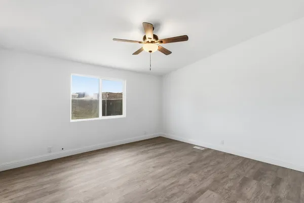 an empty room with a window and a ceiling fan