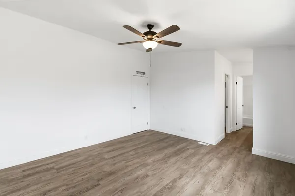 a view of a room with wooden floor and a ceiling fan