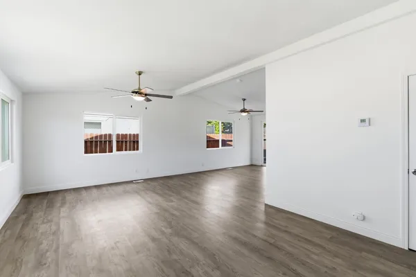 an empty room with wooden floor chandelier and windows