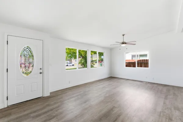 an empty room with windows and chandelier fan