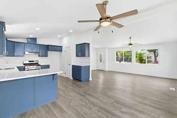 a kitchen with stainless steel appliances kitchen island granite countertop a refrigerator a stove top oven a sink and dishwasher with wooden floor