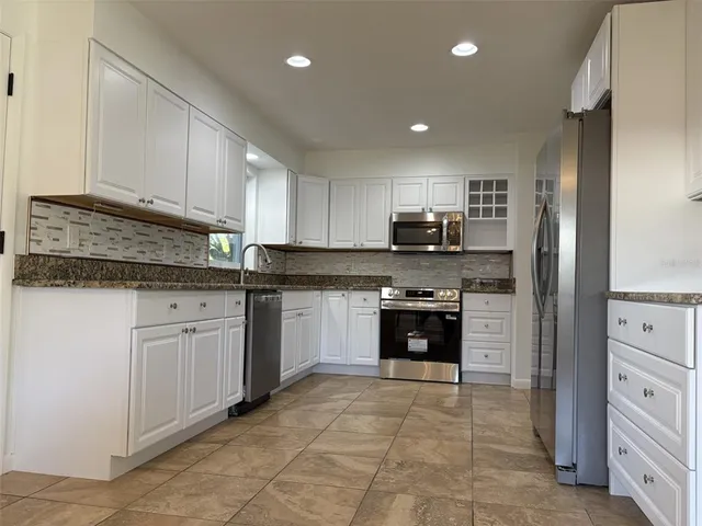 a kitchen with stainless steel appliances granite countertop a refrigerator and a stove top oven