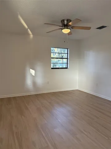 a view of an empty room with wooden floor and a window