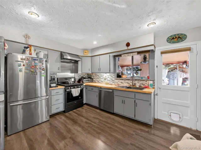 a kitchen with granite countertop stainless steel appliances a refrigerator and a stove top oven