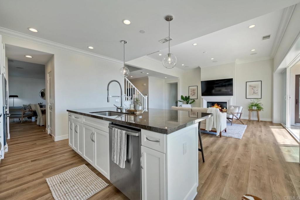 7127 Sitio Caliente Carlsbad, CA 92009 - Photo 9 of 24 a kitchen with stainless steel appliances granite countertop a sink stove and wooden floor