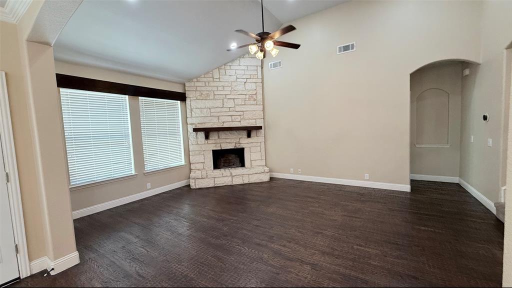 4203 Magnolia Road Melissa, TX 75454 - Photo 11 of 20 Unfurnished living room with arched walkways, a ceiling fan, a stone fireplace, lofted ceiling, and dark wood-style floors
