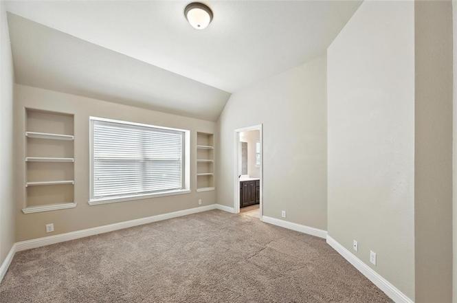 4203 Magnolia Road Melissa, TX 75454 - Photo 16 of 20 Empty room featuring built in shelves, healthy amount of natural light, light colored carpet, and vaulted ceiling