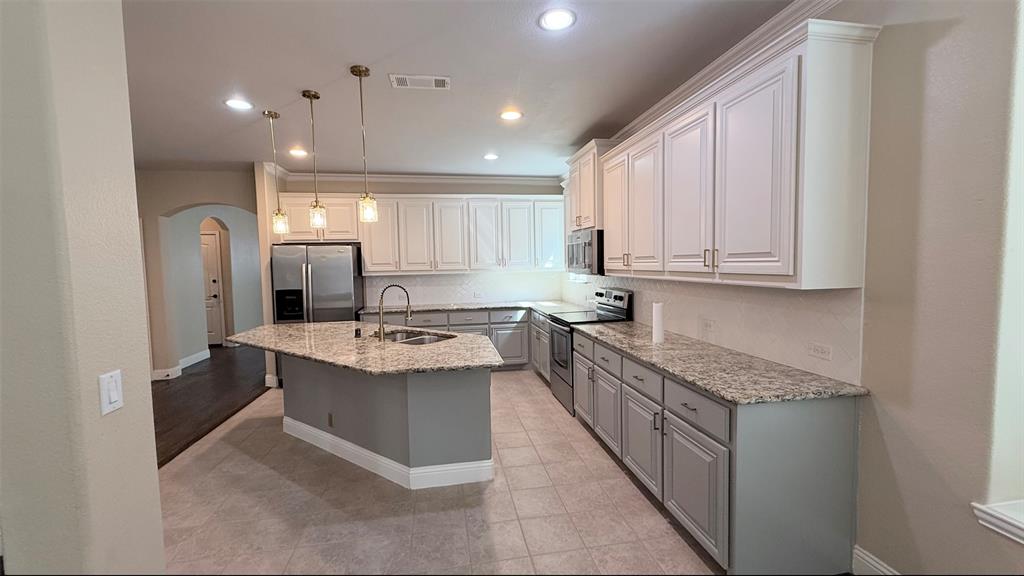4203 Magnolia Road Melissa, TX 75454 - Photo 9 of 20 Kitchen featuring arched walkways, stainless steel appliances, light stone countertops, pendant lighting, and tasteful backsplash