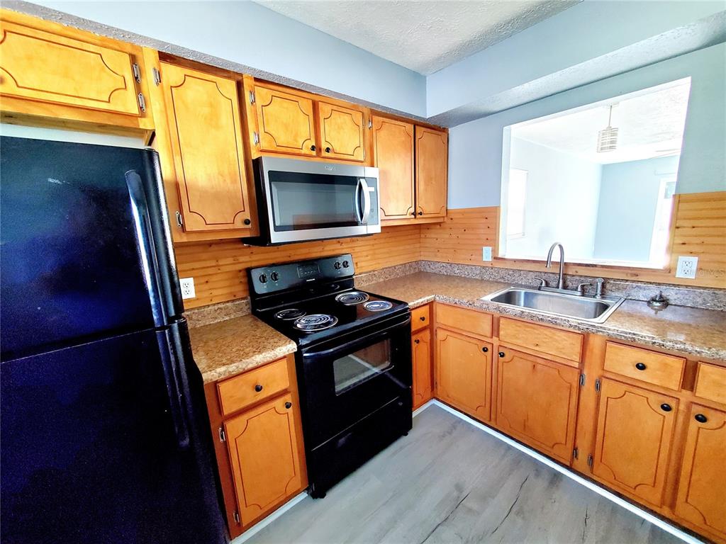 5838 Sun Glo Avenue Port Richey, FL 34668 - Photo 7 of 19 a kitchen with stainless steel appliances granite countertop a stove a sink and a microwave