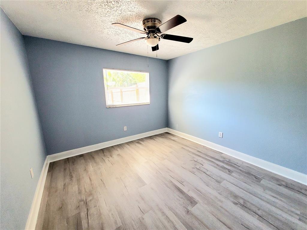 5838 Sun Glo Avenue Port Richey, FL 34668 - Photo 8 of 19 an empty room with a window and a ceiling fan