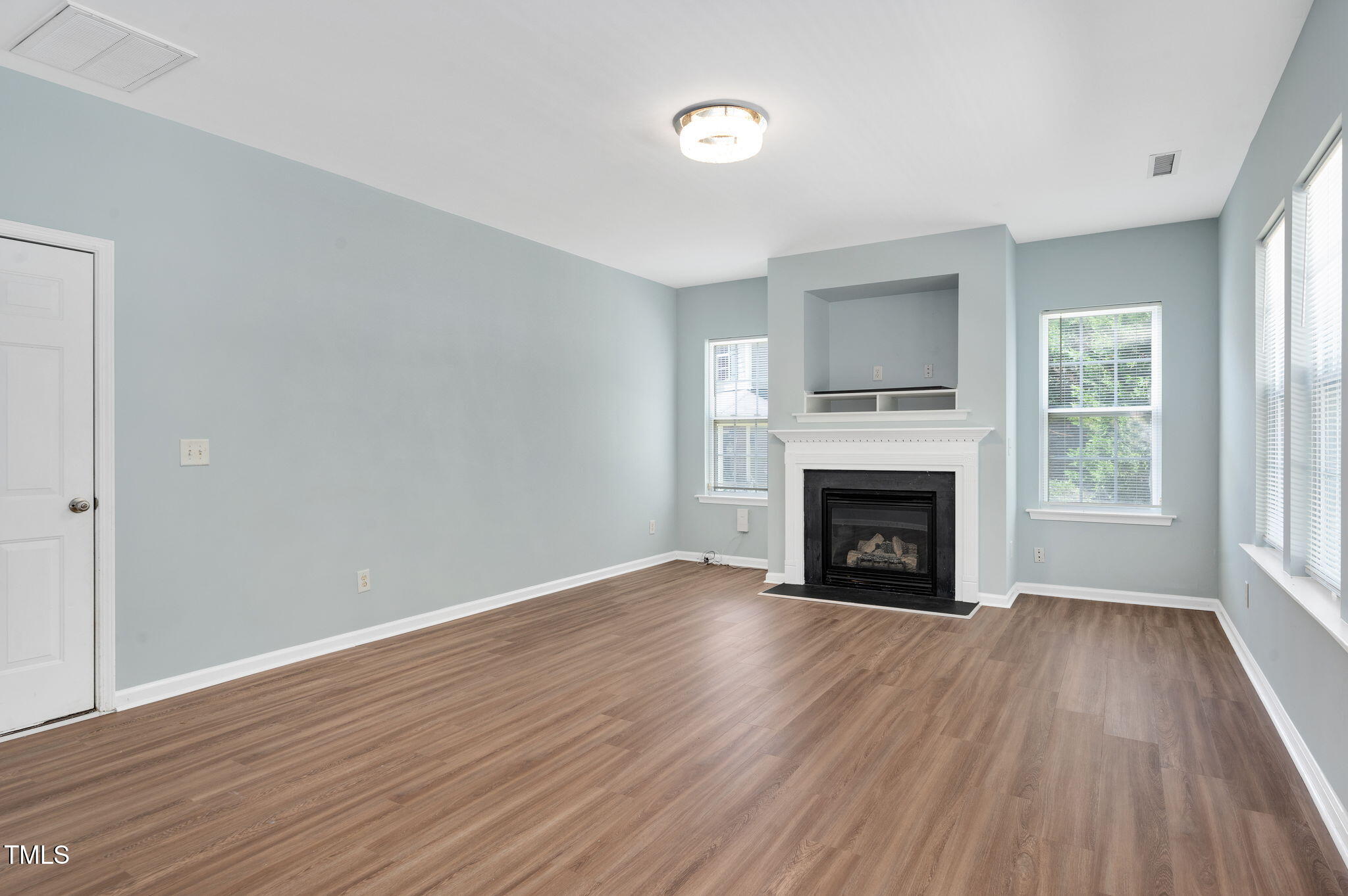 3805 Mike Levi Court Raleigh, NC 27610 - Photo 18 of 34 an empty room with wooden floor fireplace and windows